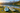 Two unbranded inflatable paddle boards on grass beside a calm mountain lake