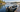 Small aluminum fishing boat secured beside a wooden dock on a calm lake
