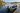 Small aluminum fishing boat secured beside a wooden dock on a calm lake