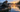 Angler lowering a portable fish finder transducer beside a kayak at sunrise