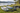 Partially deflated paddle boards and an electric pump arranged for packing beside a lake